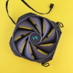 Studio shot of a black computer cooling fan on a vivid yellow backdrop.