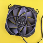 Black computer cooling fan with wire on vibrant yellow background. Ideal for technology content.