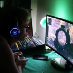 A dedicated gamer using a headset and controller while engrossed in a game, illuminated by green lights.